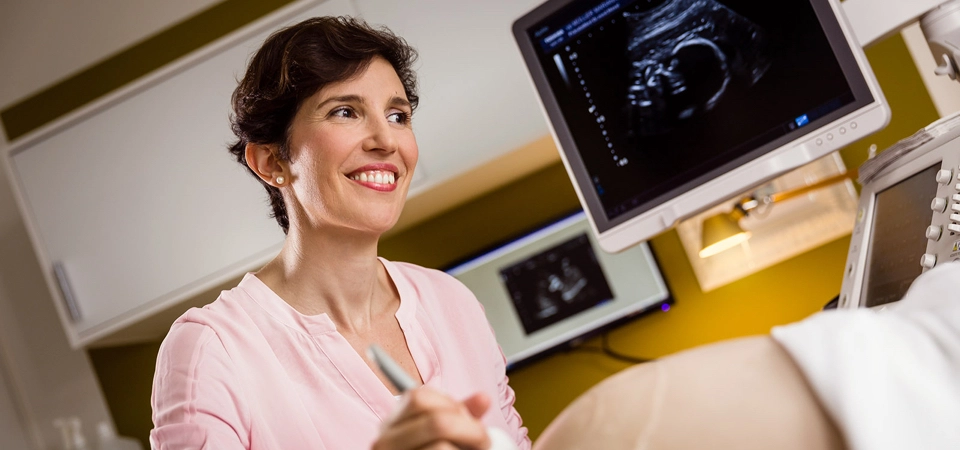 Frau Dr. Pineda lächelnd bei einer Ultraschalluntersuchung.